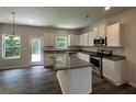 Modern kitchen features white cabinets, stainless steel appliances, and a granite island with a breakfast bar at 45 Heyman Dr, Covington, GA 30016