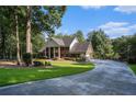 Brick home with a long driveway, mature trees, and lush green grass at 402 Clyde Ct, Mcdonough, GA 30252
