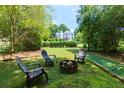 Secluded backyard setting with a fire pit, bocce court, and mature trees at 130 Hamilton Way, Roswell, GA 30075