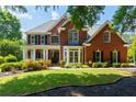 Charming two-story red brick home featuring a landscaped yard and welcoming front porch at 130 Hamilton Way, Roswell, GA 30075