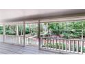 Enjoy the nature views from this outdoor covered porch with white railing and stairs at 203 Cedar Creek Ct, Acworth, GA 30101