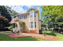 Side view of a yellow two-story house with a bay window and manicured lawn and landscaping at 75 Maygold St, Mcdonough, GA 30253