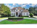 Elegant two-story home with a manicured lawn, circular driveway, and lush landscaping at 8455 Abingdon Ln, Duluth, GA 30097