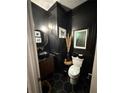 Stylish powder room with dark walls, modern fixtures, and a round mirror with black faucet at 125 Sir Lancelot Ct, Fayetteville, GA 30214