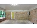 Spacious brick carport features a concrete floor, yellow entry door, and access to backyard at 4852 Pine Shadows Dr, Stone Mountain, GA 30088