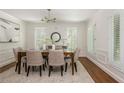 Elegant dining room with wainscoting, neutral decor, modern chandelier, and shuttered windows at 799 Birds Se Ml, Marietta, GA 30067