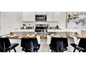 Close-up of kitchen island with granite countertop, stainless steel sink, and bar stools with place settings at 5453 Baybrook Cir, South Fulton, GA 30349