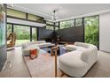 Bright living room with oversized windows, chic sofas, and views of the landscaped outdoors at 3891 Wieuca Rd, Atlanta, GA 30342