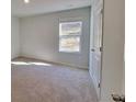 Well-lit bedroom with plush carpet, a window, and a closet with a white paneled door at 15 Barton Ln, Covington, GA 30016