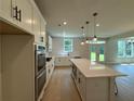 Well-lit kitchen features stainless appliances, white cabinets, and island seating with backyard view at 6945 Melody Ridge Rd, Buford, GA 30518