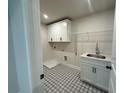 Functional laundry room with patterned floor, sink, storage and overhead cabinet at 6945 Melody Ridge Rd, Buford, GA 30518