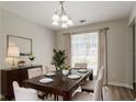 Bright dining room features modern chandelier, table set for six, elegant decor, and large window at 711 Ashley Ln, Stone Mountain, GA 30087
