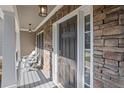 Inviting front porch with a stone exterior, comfortable seating and stylish lighting fixtures at 428 Gold Xing, Canton, GA 30114