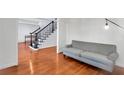 Cozy living room with hardwood floors, a gray sofa, and a view of the staircase at 5735 Lake Windsor Pkwy, Buford, GA 30518