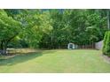 The property boasts a large, well-maintained backyard, partially fenced, with storage shed, and surrounded by mature trees at 5340 Harris Creek Dr, Cumming, GA 30040