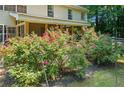 A beautifully landscaped backyard with colorful roses surrounds a screened porch with view of a lush wooded property at 5340 Harris Creek Dr, Cumming, GA 30040