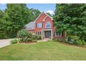 Charming two-story red brick home with black shutters, lush landscaping, and a well-manicured lawn at 505 Armor Knl, Powder Springs, GA 30127