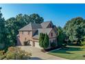 Charming brick home featuring a three-car garage and mature trees at 5347 Harbury Cv, Suwanee, GA 30024