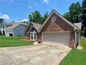 Charming brick home featuring an attached two-car garage and well-maintained front yard with bay window at 5022 Anclote Dr, Alpharetta, GA 30022