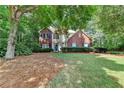 Beautiful two-story home with a manicured lawn, brick accents, and mature trees providing shade and privacy at 6520 Fairfield Trce, Suwanee, GA 30024