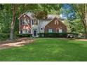 Beautiful home with a lush green lawn, brick accents, blue shutters, and mature trees at 6520 Fairfield Trce, Suwanee, GA 30024