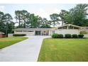 Inviting one-story home featuring a well-manicured lawn, and a long driveway leading to the blue garage door at 2302 Springside Way, Decatur, GA 30032