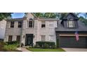 Front elevation showcasing a white-brick home with a black two-car garage and a manicured front yard at 4385 Pinehollow Court Ct, Alpharetta, GA 30022