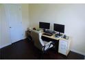 Home office featuring wood floors, a modern desk setup with dual monitors, and a white storage cabinet at 7104 Georges Way, Morrow, GA 30260