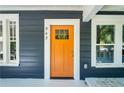 Close-up of a vibrant orange front door with glass paneling and white trim, complemented by windows and siding at 943 Rose Sw Cir, Atlanta, GA 30310