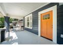 Inviting front porch with a seating area and a vibrant orange front door with large window for natural light at 943 Rose Sw Cir, Atlanta, GA 30310