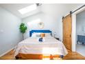 Sunlit main bedroom with vaulted ceiling, skylight, blue headboard and sliding barn door to the bathroom at 2411 Fair Lane Ln, Decatur, GA 30032