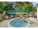 Backyard oasis featuring a kidney-shaped pool, patio furniture under umbrellas, and lush landscaping for ultimate relaxation at 6430 Banbury Se Ct, Mableton, GA 30126