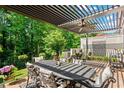 Relaxing outdoor patio with a pergola, ceiling fan, dining table, grill, and lush greenery at 4486 Huffman Drive Ne Dr, Roswell, GA 30075