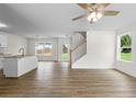 Open-concept living area boasts hardwood floors, staircase, ceiling fan, and natural light from large windows at 5350 Mercedes Dr, Cumming, GA 30041