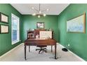 Home office with dark green walls, wooden desk, plush carpeting and a bright window at 4140 Prince Charles Dr, Duluth, GA 30097