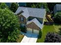 Aerial view of charming home with brick accents, two-car garage, and lush green surroundings at 213 Roseman Way, Woodstock, GA 30188