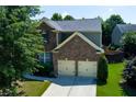 Charming two-story home featuring a brick facade, two-car garage, and a well-manicured lawn at 213 Roseman Way, Woodstock, GA 30188