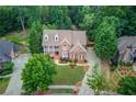 Stunning aerial view of a brick house with lush greenery and a well-maintained lawn at 2748 Hidden Falls Dr, Buford, GA 30519