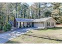 Inviting one-story home featuring a two-car garage, manicured lawn, dark shutters, and a lush backdrop of trees at 1373 W Prospect Dr, Lawrenceville, GA 30043