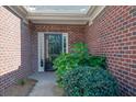Close-up of a brick entryway featuring a black front door with sidelight, framed by lush green shrubbery at 1550 Rolling View Dr, Cumming, GA 30040