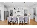 Bright kitchen with a large center island, pendant lighting, stainless appliances, and open shelving at 6820 Colfax Ave, Cumming, GA 30040