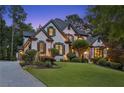 Elegant two-story home with a well-manicured lawn and beautiful landscaping at twilight at 6455 Darely Ct, Cumming, GA 30040