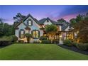 Charming two-story home with a well-manicured lawn and beautiful landscaping at twilight at 6455 Darely Ct, Cumming, GA 30040