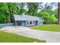 The beautiful, light blue home features a carport and a large driveway, surrounded by lush landscaping at 9025 Huntwood Ln, Riverdale, GA 30274