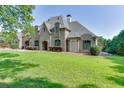Elegant stone home with lush green lawn offers a welcoming facade with mature landscaping and arched entry at 2871 Hosch Valley Rd, Buford, GA 30519