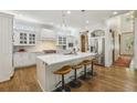 Modern white kitchen featuring a large center island, stainless steel appliances, and hardwood flooring at 1363 Sylvan Ne Cir, Brookhaven, GA 30319