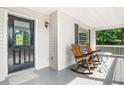 Inviting front porch featuring rocking chairs and a small table with a black front door at 4292 Hurt Bridge Rd, Cumming, GA 30028