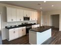 Modern kitchen with white cabinets, stainless steel appliances, and a center island with black countertops at 3536 Dogwood Pass, Lithonia, GA 30038