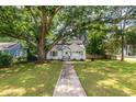 Charming white home with a quaint blue door, nestled under a large tree with a sprawling green lawn at 2010 2Nd Ave, Decatur, GA 30032
