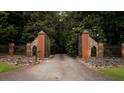 Private gated entrance featuring stone pillars, metal fencing, and tree-lined driveway at 114 Lees Lake Rd, Fayetteville, GA 30214